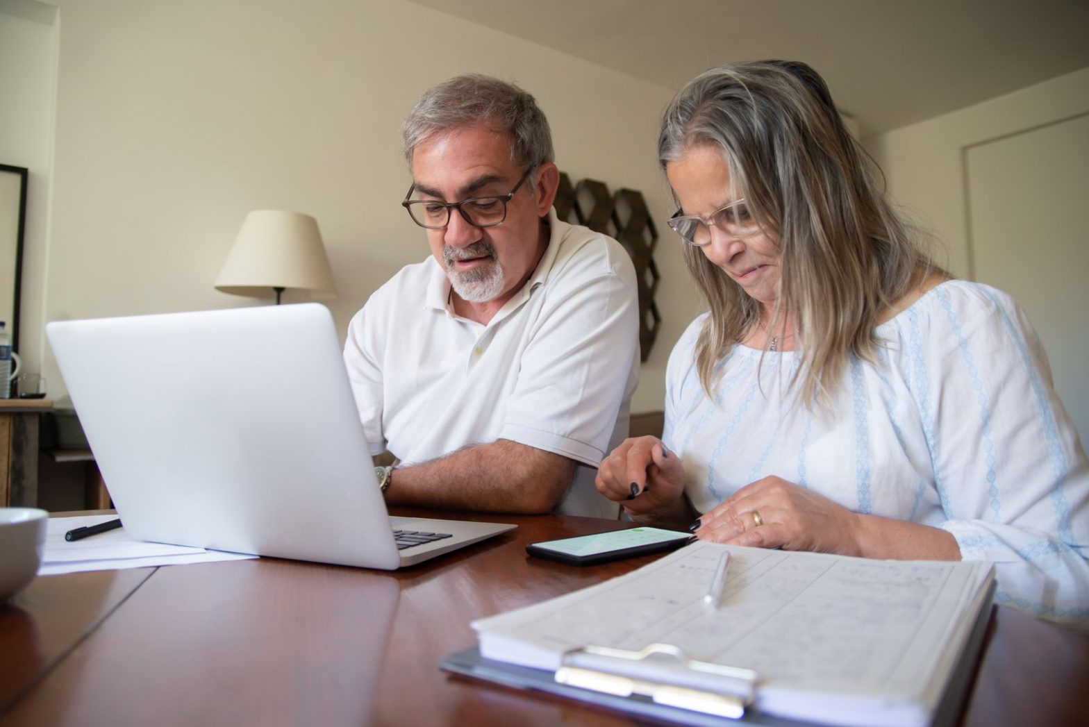 Senior couple reviewing documents with a laptop at home