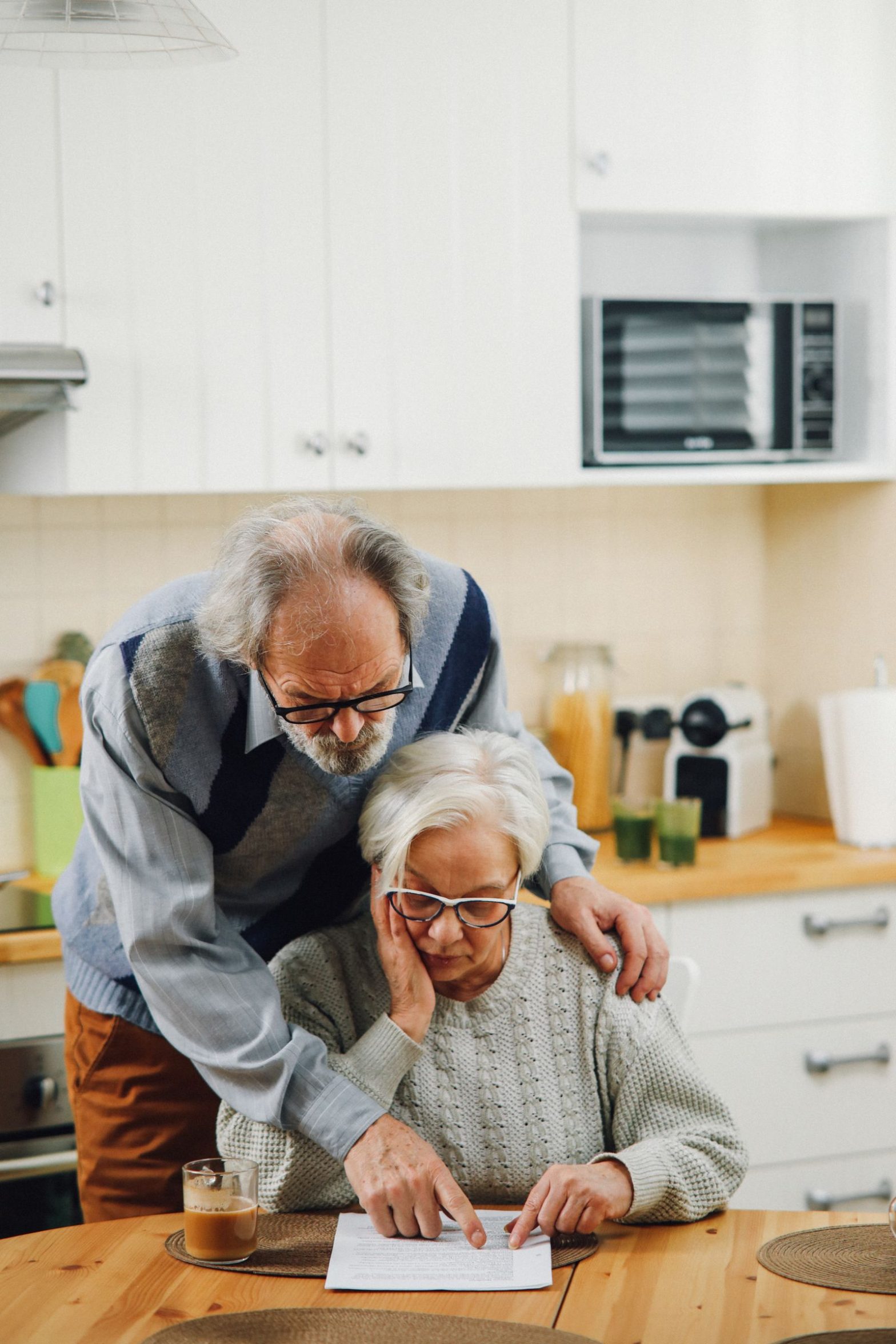 Elderly couple reading documents together at a kitchen table