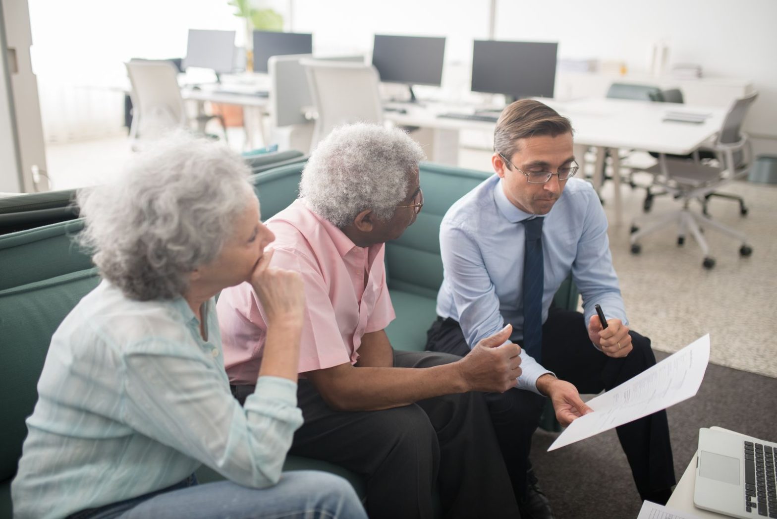 Elderly man and woman talking with an advisor in an office
